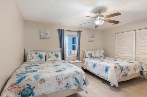 a bedroom with two beds and a ceiling fan at Sea Breeze 101 Beach Bliss in St. Pete Beach