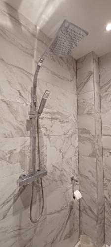 a shower in a bathroom with a marble wall at The Pearl Manor in Watford