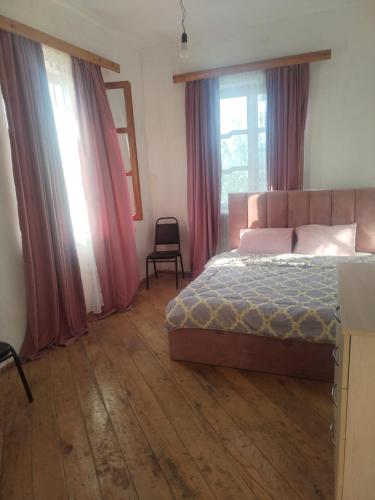 a bedroom with a bed and a chair and windows at Farmer's Guest House in Telavi