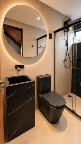 a bathroom with a black toilet and a mirror at Chalé 17 I Conforto e Lazer na Serra I Gravatá PE in Gravatá