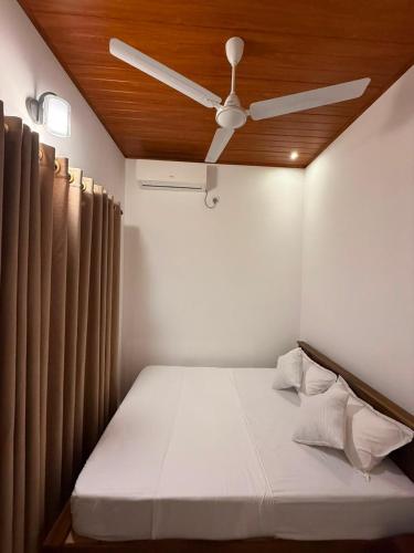 a bed with a ceiling fan in a room at Yalora Villa Kataragama in Kataragama