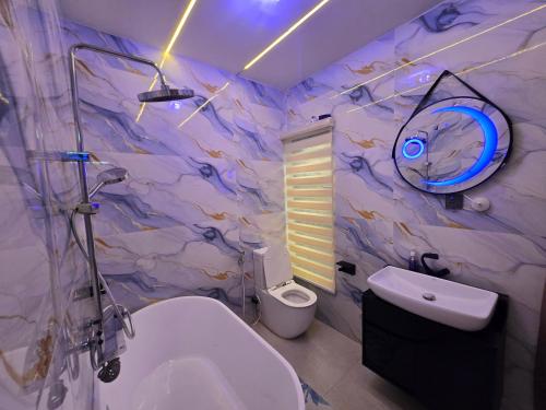 a bathroom with a white toilet and a marble wall at Virginhomes apartment in Jibowu