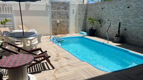 a swimming pool on a patio with a table and an umbrella at Caueira Beach House in Itaporanga dʼAjuda
