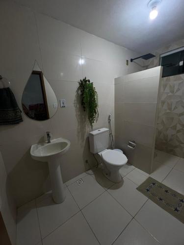 a white bathroom with a toilet and a sink at Caueira Beach House in Itaporanga dʼAjuda