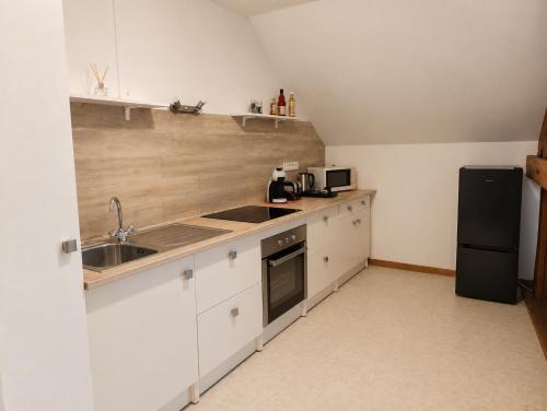 a kitchen with white cabinets and a sink and a refrigerator at La Clef des vignes 4 in Roye