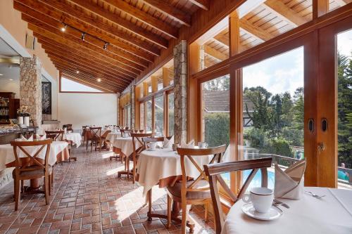 a restaurant with tables and chairs and large windows at Hotel Saint Michel in Monte Verde