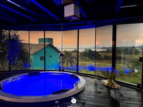 a large blue tub in a room with a large window at Ibiraquera Life in Praia do Rosa