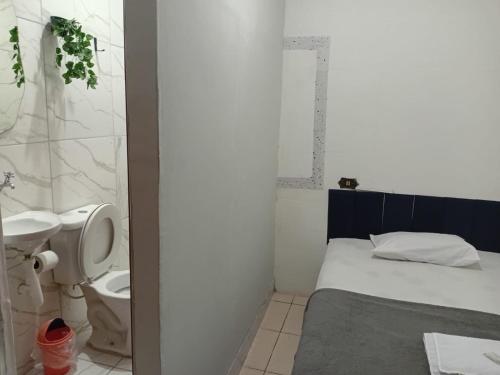 a small bathroom with a bed and a toilet at Pousada Central Itabirito in Itabirito