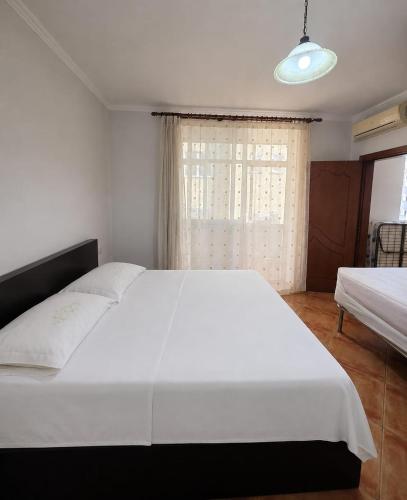 a bedroom with a large white bed and a window at APP Apartament in Durrës