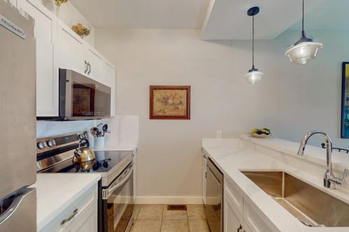 a white kitchen with a sink and a stove at Rivergrass by Property Valet in Blue Mountains