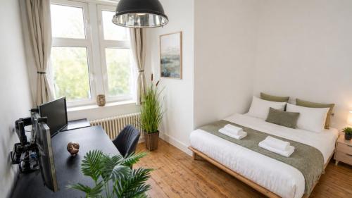 a bedroom with a bed and a desk with a computer at NUJU Rentals - 4-Zimmer, 10 Gäste, Wintergarten & Terrasse & Parkplatz in Bielefeld