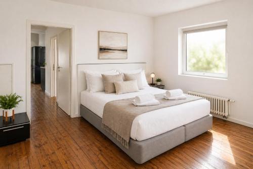 a white bedroom with a large bed and a window at NUJU Rentals - 4-Zimmer, 10 Gäste, Wintergarten & Terrasse & Parkplatz in Bielefeld