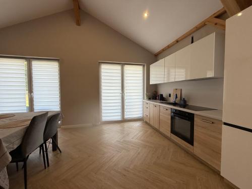 a kitchen with white cabinets and a table with chairs at Chill and Grill Apartments in Wola Smolana