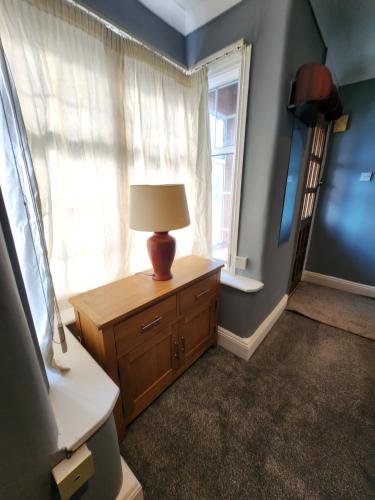 a room with a lamp on a dresser and a window at The Iris in Grays Thurrock