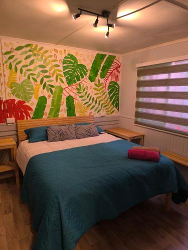a bedroom with a bed with a painting on the wall at Isla Yu Patagonia 2 in Puerto Natales