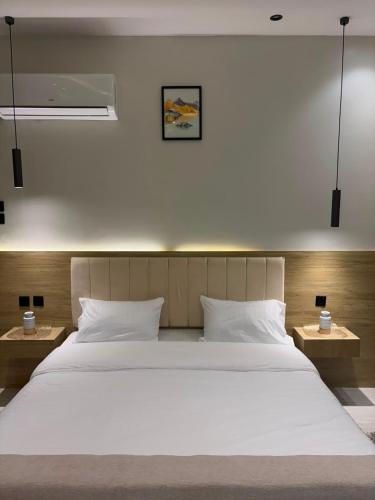 a large white bed in a room with two tables at لين سويت in Khamis Mushayt