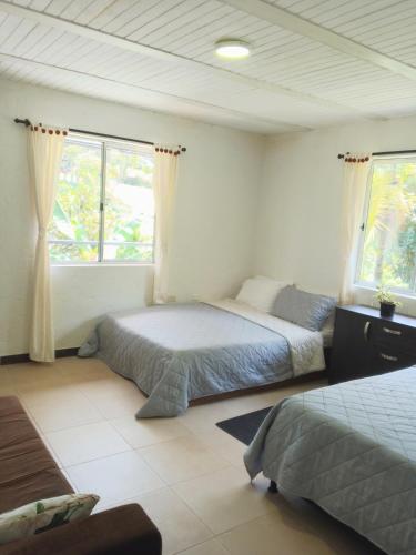 a bedroom with two beds and two windows at Cabaña con Jacuzzi Privado en El Peñol El palmar lodge in Chiquinquirá