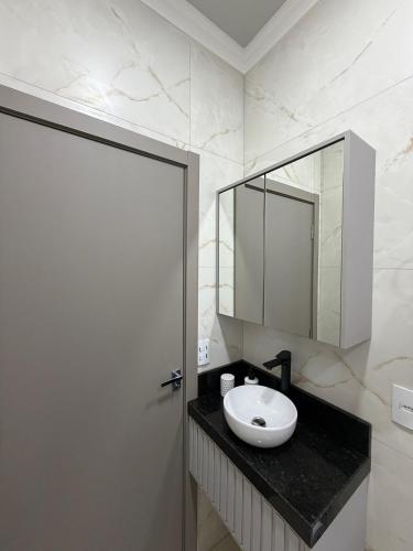 a bathroom with a sink and a mirror on a counter at Bairro Universtário - Central in Cascavel