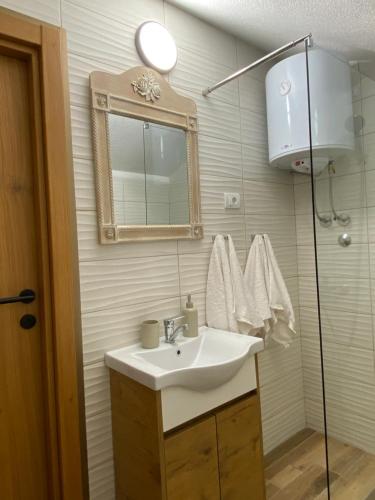 a bathroom with a sink and a mirror and a shower at Apartmani Dora in Mataruška Banja