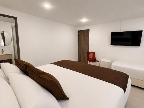 a bedroom with a bed and a tv on the wall at Zentio Hotel in Bogotá