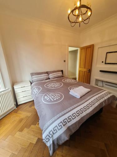 a large bed in a bedroom with a chandelier at The Carnation in Grays Thurrock
