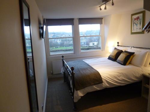 a bedroom with a large bed with two windows at Edgar Townhouse in Bath