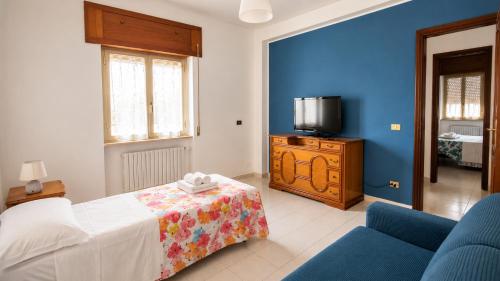 a bedroom with a bed and a tv and a blue wall at La Tana della Volpe in Tempera