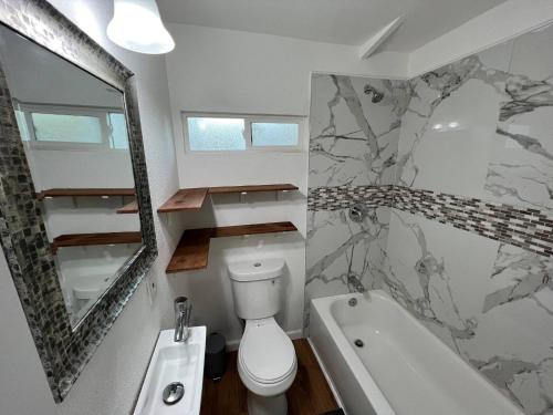 a bathroom with a toilet and a tub and a sink at Le Petite Willow - Guesthouse in Modesto