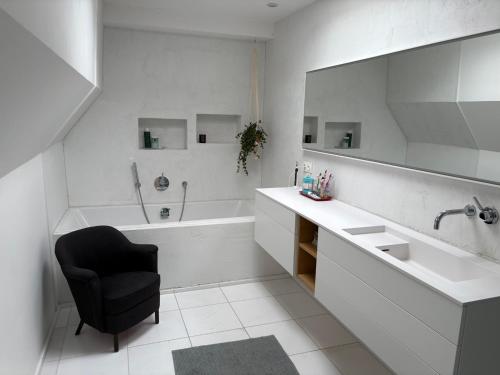 ein Badezimmer mit Waschbecken, Badewanne und Stuhl in der Unterkunft Woonboot Adonia in Turnhout