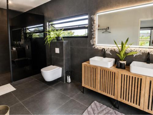 a bathroom with two sinks and a toilet and a mirror at Guesthouse AngaLampoe in Lelydorp