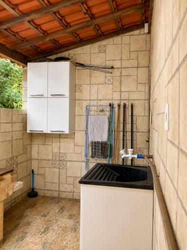 a kitchen with a sink and a tiled wall at Chalé Sonho Meu Penedo in Itatiaia