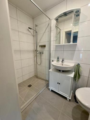 a white bathroom with a shower and a sink at Ferienwohnung Stefan in Wallertheim