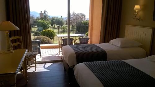 a hotel room with two beds and a balcony at Hotel Bellerive in Rasteau
