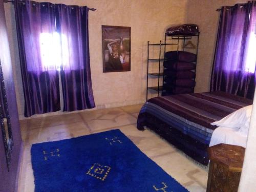 a bedroom with purple curtains and a bed and a blue rug at La Kasbah d'Ouzoud in Ouzoud