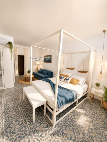 a bedroom with a white canopy bed and a couch at Le Tartarughe - Rooms and Apartments - in Milazzo
