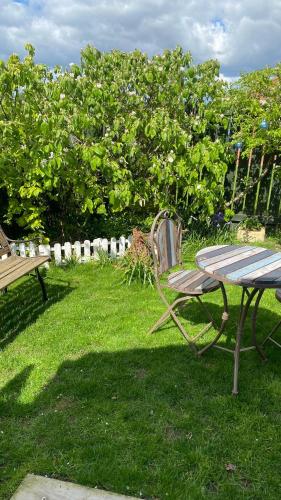 a table and a chair in the grass with a table and a bench at Chez Little Black Cat in Patrington