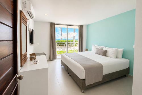 a bedroom with a bed and a large window at Hotel San Luis Beach House By OxoHotel in San Andrés