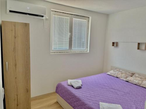a bedroom with a purple bed and a window at DAMIEN apartments in Ohrid