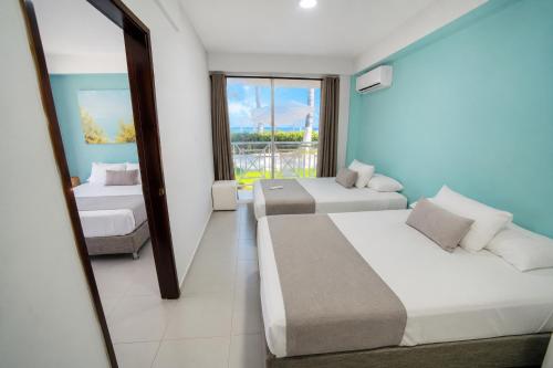 a hotel room with two beds and a mirror at Hotel San Luis Beach House By OxoHotel in San Andrés
