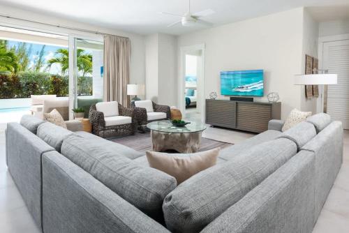 a living room with a large couch and a tv at Second Wind Villa in Long Bay Hills