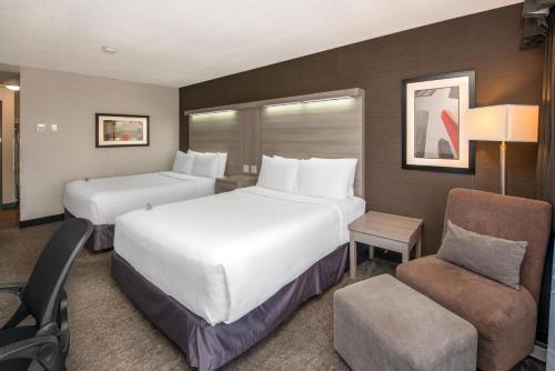 ein Hotelzimmer mit zwei Betten und einem Stuhl in der Unterkunft Coast Calgary University Area Hotel by APA in Calgary