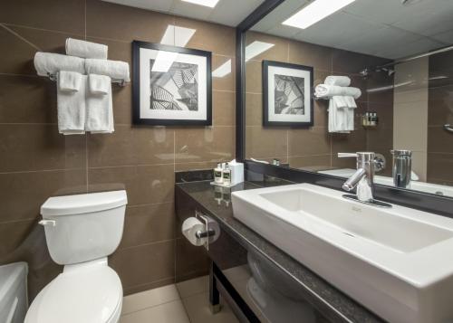 ein Badezimmer mit Waschbecken, Toilette und Spiegel in der Unterkunft Coast Calgary University Area Hotel by APA in Calgary