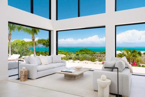 a living room with white furniture and large windows at Beachwood Villa in Turtle Cove