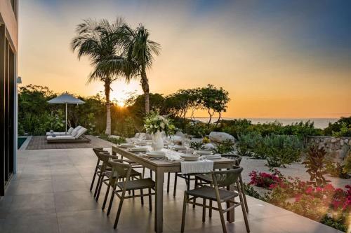a dining table and chairs on a patio with the ocean at Beachwood Villa in Turtle Cove