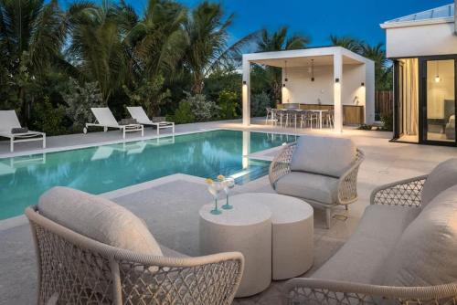a swimming pool with chairs and a table next to a house at Villa Seadream - Upper East Side Enclave #16 in Long Bay Hills