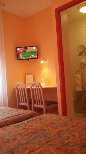 um quarto de hotel com uma cama, uma secretária e uma televisão em Maison Hôtel Aux Cerisiers em La Forêt-Fouesnant