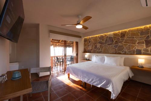 a bedroom with a bed and a stone wall at La Posada Hotel Boutique in Manzanillo