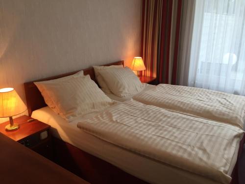 a bedroom with a bed with white sheets and pillows at Kurpark-Hotel in Bad Salzuflen