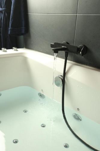 a bath tub with water pouring from a faucet at Lasuitesecretetdetente in Beauvais