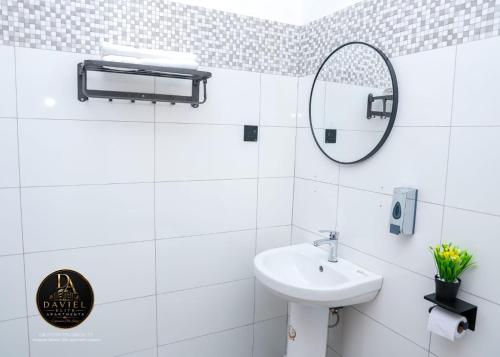 a white bathroom with a sink and a mirror at Daviel Elite Apartments in Dodoma
